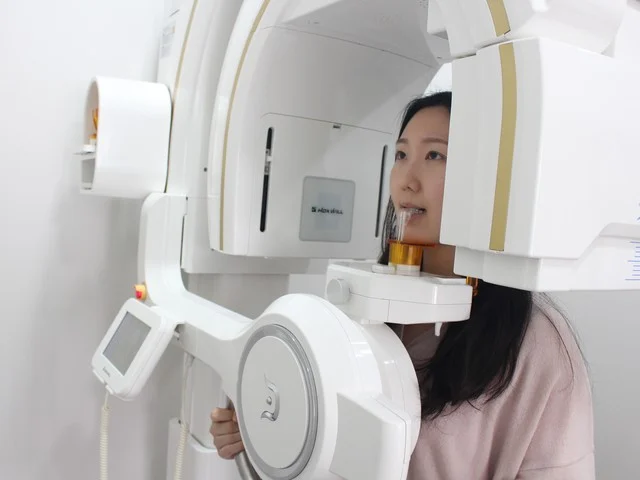 환자가 디지털 3D CT 촬영 장비 앞에 서서 촬영을 받는 모습.
